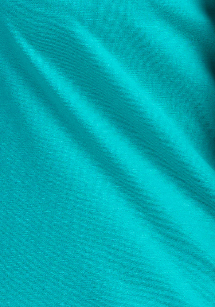 A close-up of the Woolx Elena 3/4 Sleeve V Neck in Cool Jade reveals visible texture and gentle folds, casting soft diagonal shadows across the merino wool fabric.