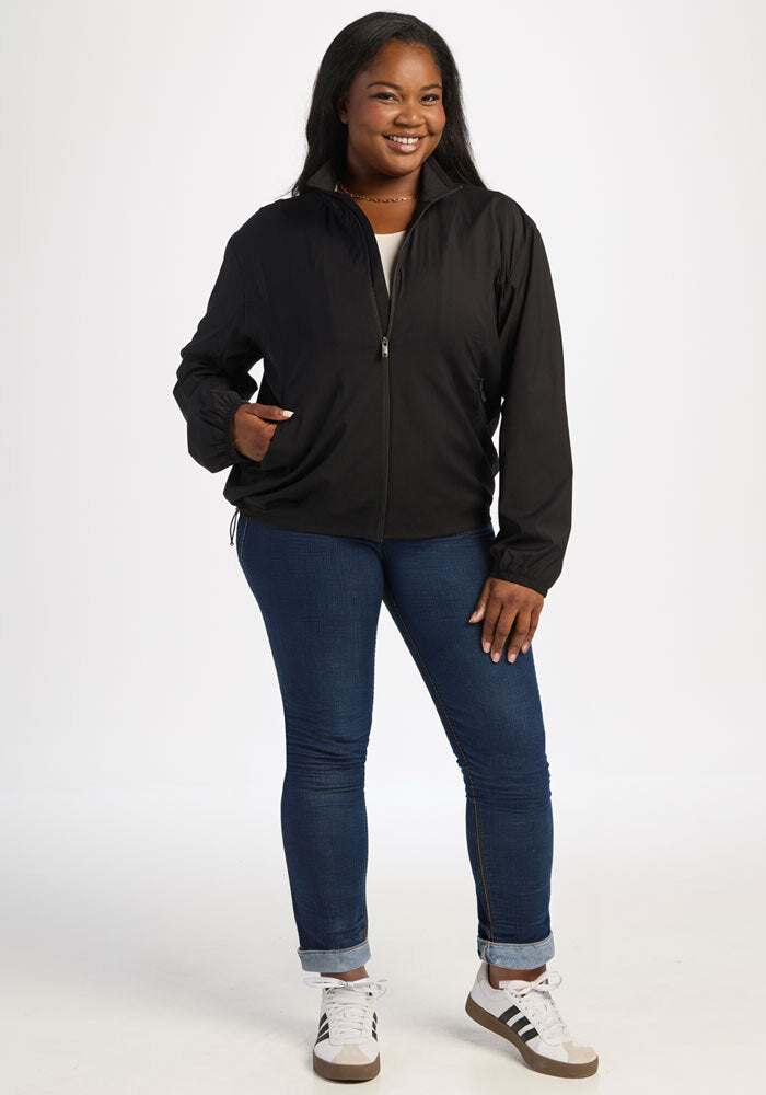 Woman standing and smiling in the Woolx Cooper Windbreaker - Black, with zip pockets and all-season woven fabric.