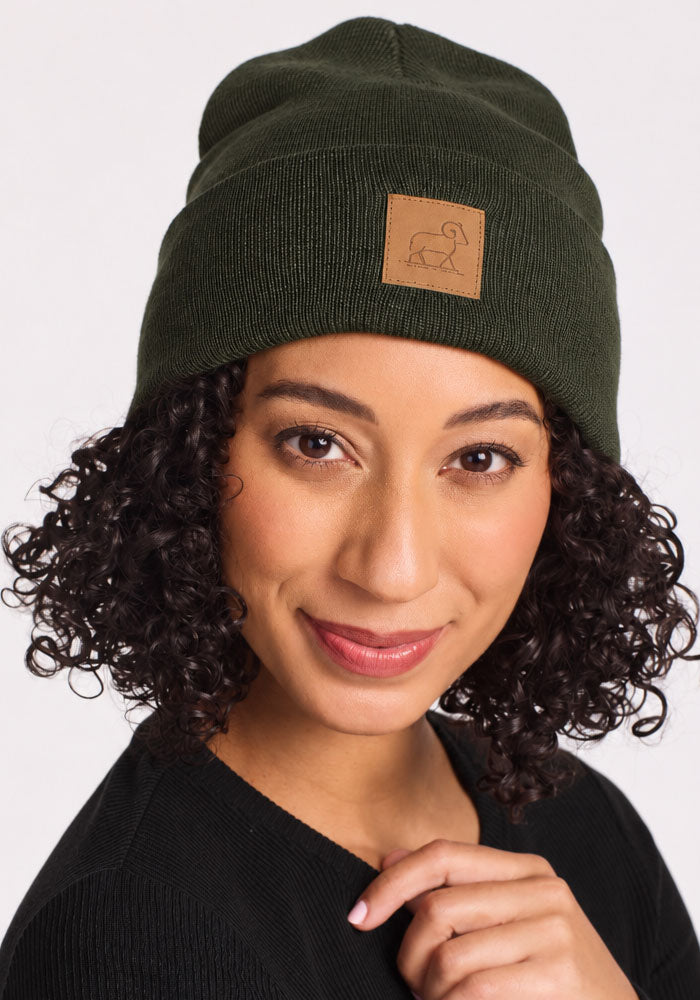 Smiling woman in Woolx Baylor Beanie - Duffel Bag, curly hair out, brown patch detail, black shirt.