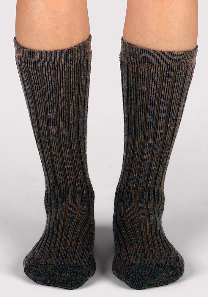 A pair of feet wears Woolx Womens Joey Mid Calf Socks in Dark Espresso, thick ribbed merino wool socks reaching mid-calf, shown against a plain light background.
