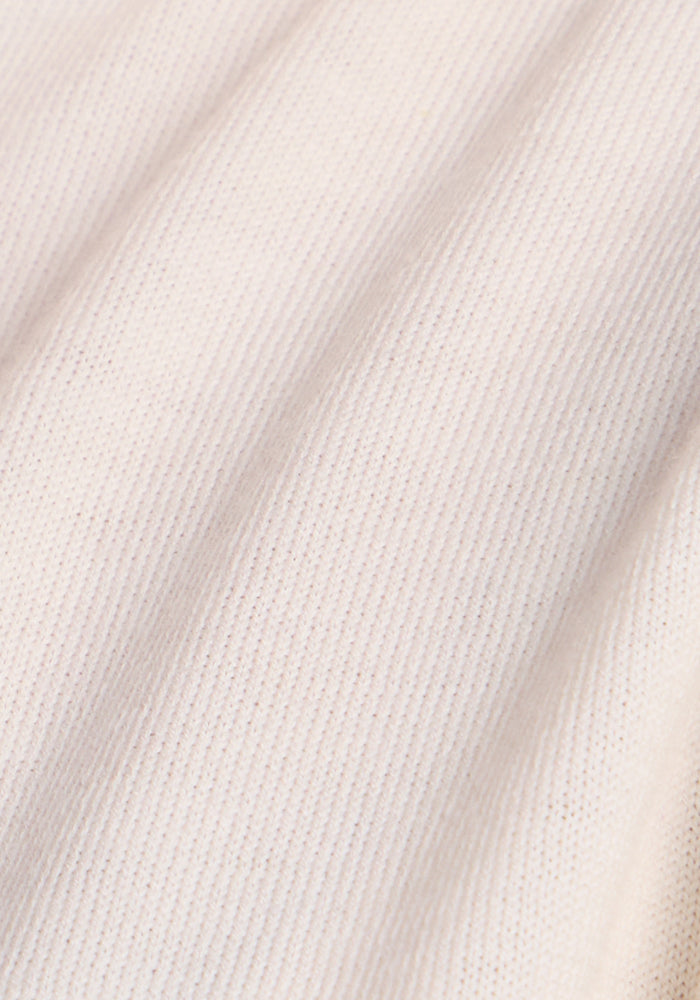 Close-up of the Woolx Collins Half Zip Sweater in Dewdrop Pearl, featuring a light beige ribbed merino wool texture with soft diagonal folds and a fine vertical knit pattern.