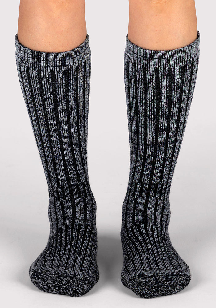 A pair of legs wearing Woolx Womens Joey Mid Calf Socks in Dark Navy Marled stands on a light gray surface.