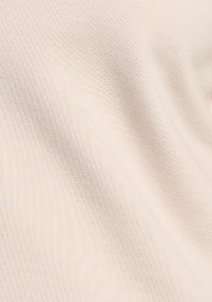 Close-up of the Woolx Sadie Baselayer Top in Ecru, showing soft, textured fabric and subtle folds.