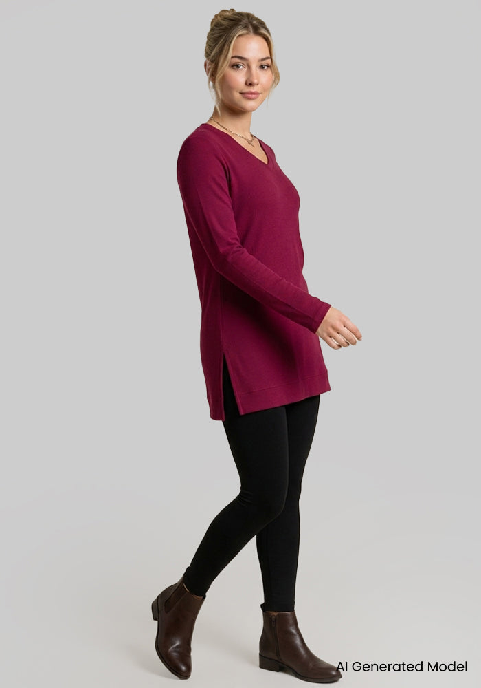 Woman in a Woolx Evie Petite Tunic in Beet Red, black leggings, and brown ankle boots against a gray background.