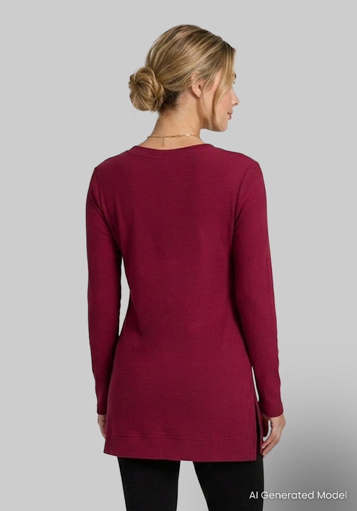 Woman facing away in a Woolx Evie Petite Tunic - Beet Red and black leggings, low bun, gray background.