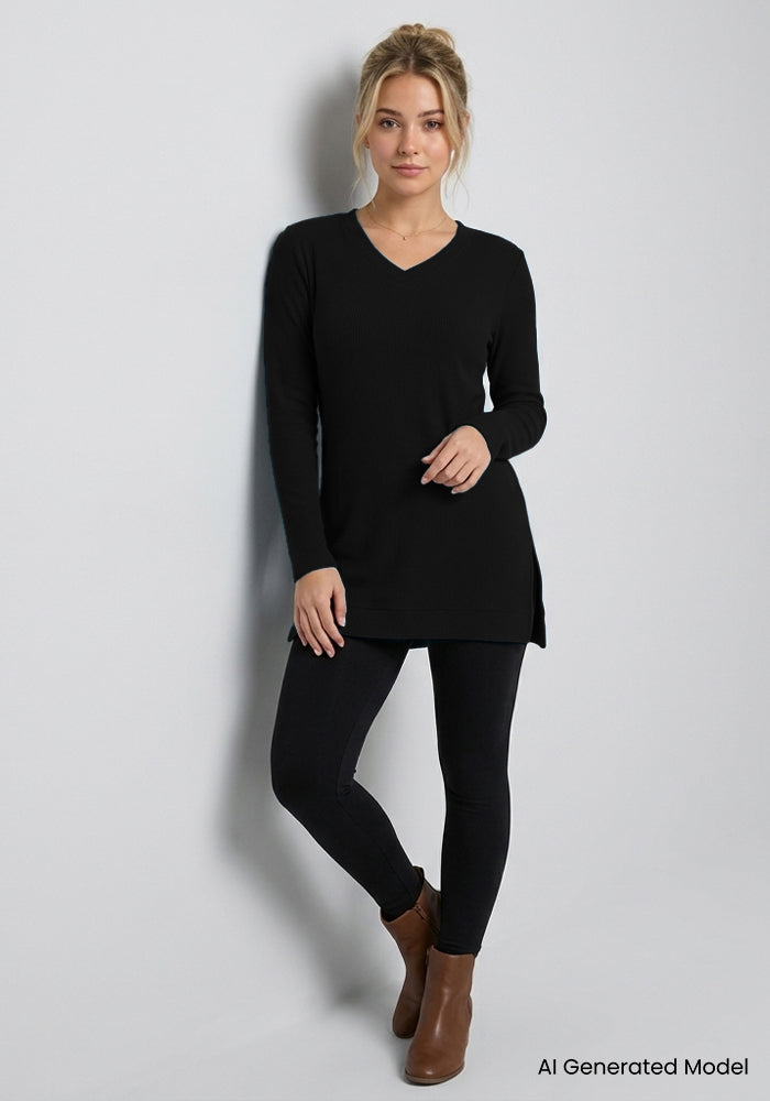 Woman in Woolx Evie Petite Tunic - Black, black leggings, brown ankle boots, stands by a light gray wall.