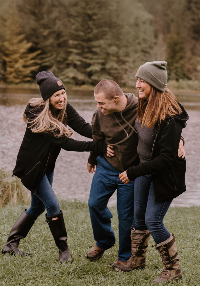 Three people standing together outdoors with a natural background