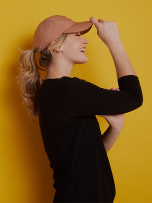 Model wearing salmon Frankie hat against yellow wall mobile size