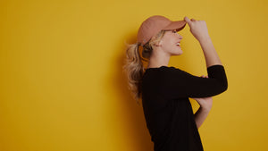 Model wearing salmon Frankie hat against yellow background