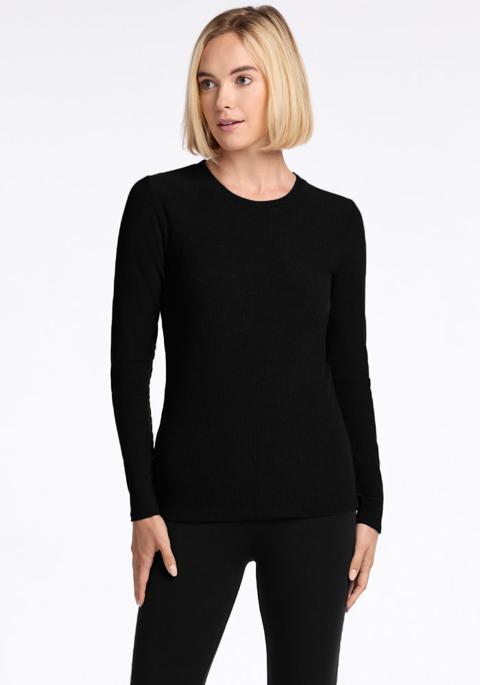 Woman with blonde bob wears Woolx Hadley Petite Crew - Black, paired with pants, against a white background.