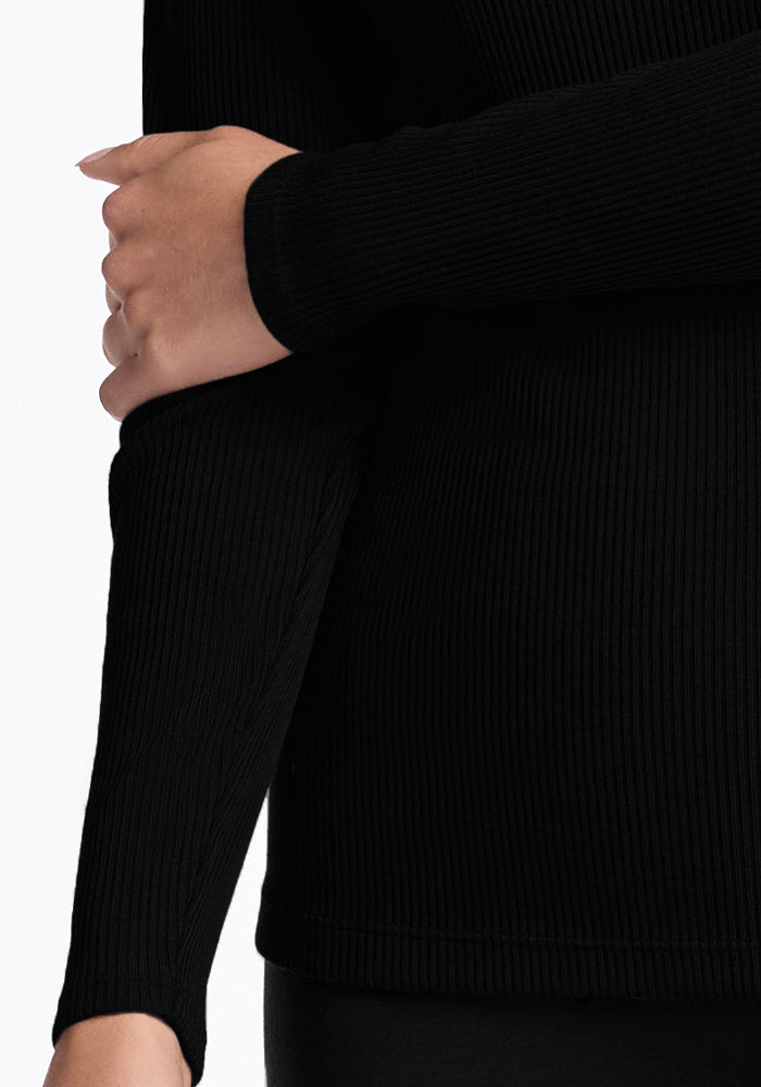 A person wearing the Woolx Hadley Petite Crew in black with one arm crossed over their body.