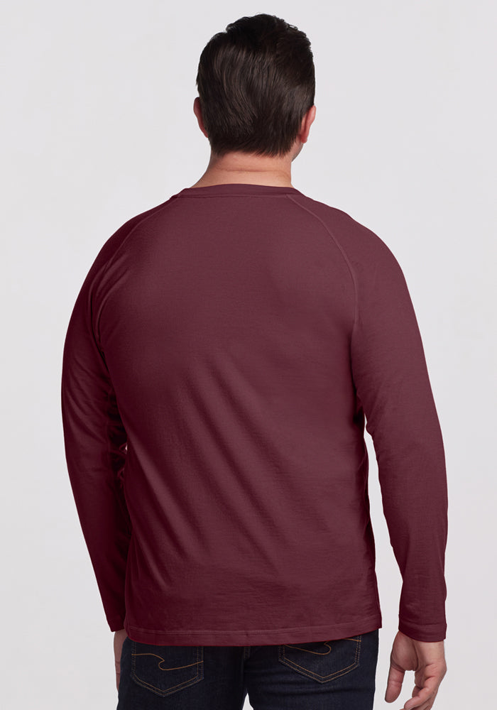 A person with short dark hair is shown from behind, wearing the Woolx Essential Tee - Grape Harvest and dark jeans against a plain light background.