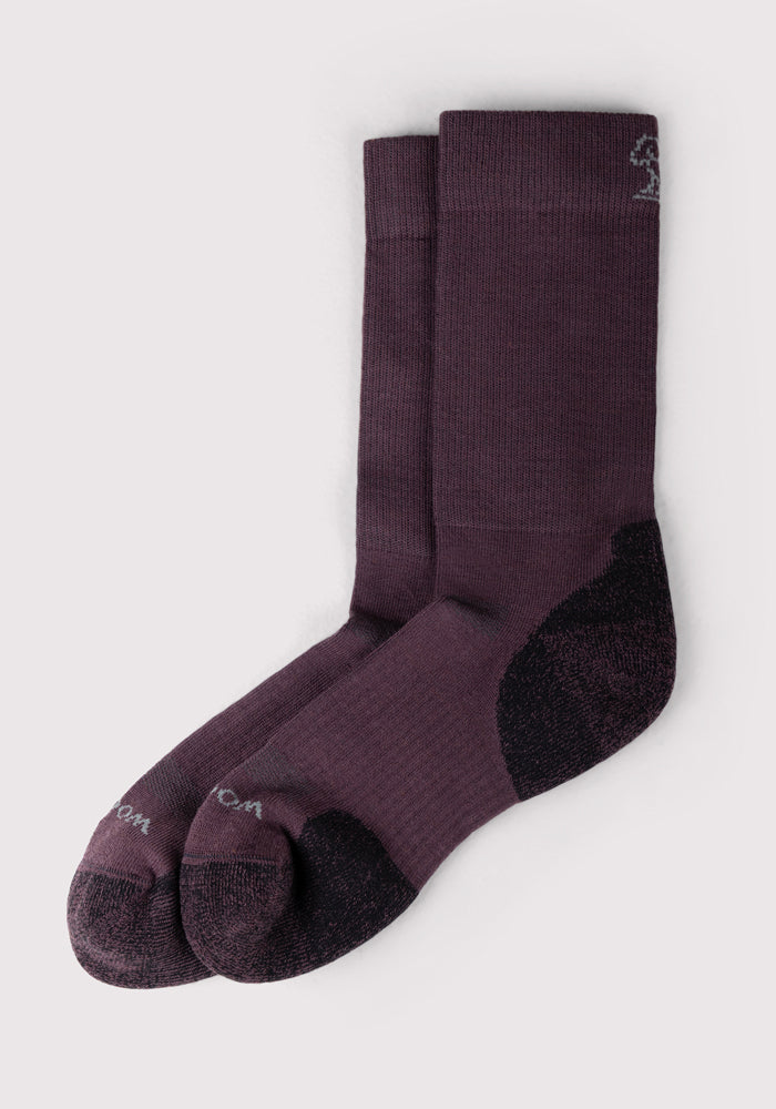 The Woolx Womens Harbor Crew Sock in Grape Harvest features dark purple, moisture-wicking fabric with black toe and heel accents, displayed side by side on a light background.