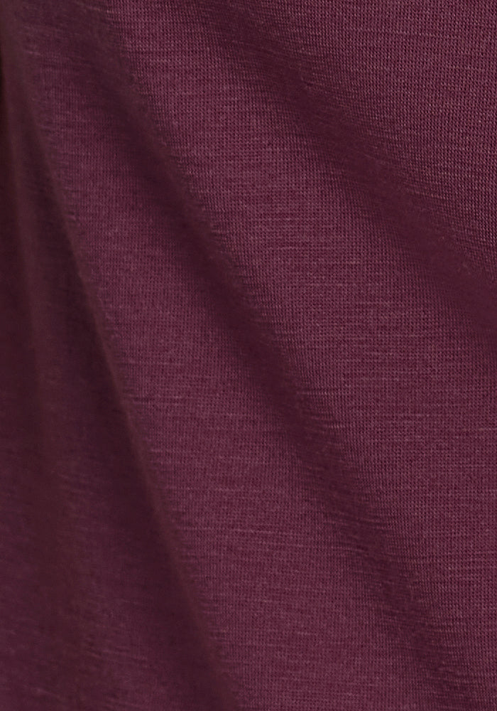 Close-up of the Woolx Ryann Hoodie in Grape Harvest shows its soft, maroon-colored fabric with diagonal folds, highlighting the quality and comfort of this women’s travel hoodie.