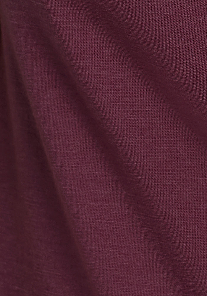 Close-up of the Woolx Summit Polo in Grape Harvest: maroon-hued fabric with soft texture and visible weave, showing subtle folds and shadows—perfect for high-performance athletic wear.