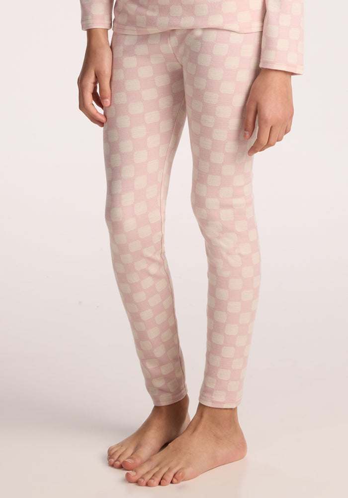 A child stands barefoot in Woolx Kids Explorer Base Layer Bottoms in Hopscotch Pink, with their body shown from shoulders to feet against a plain light background. 