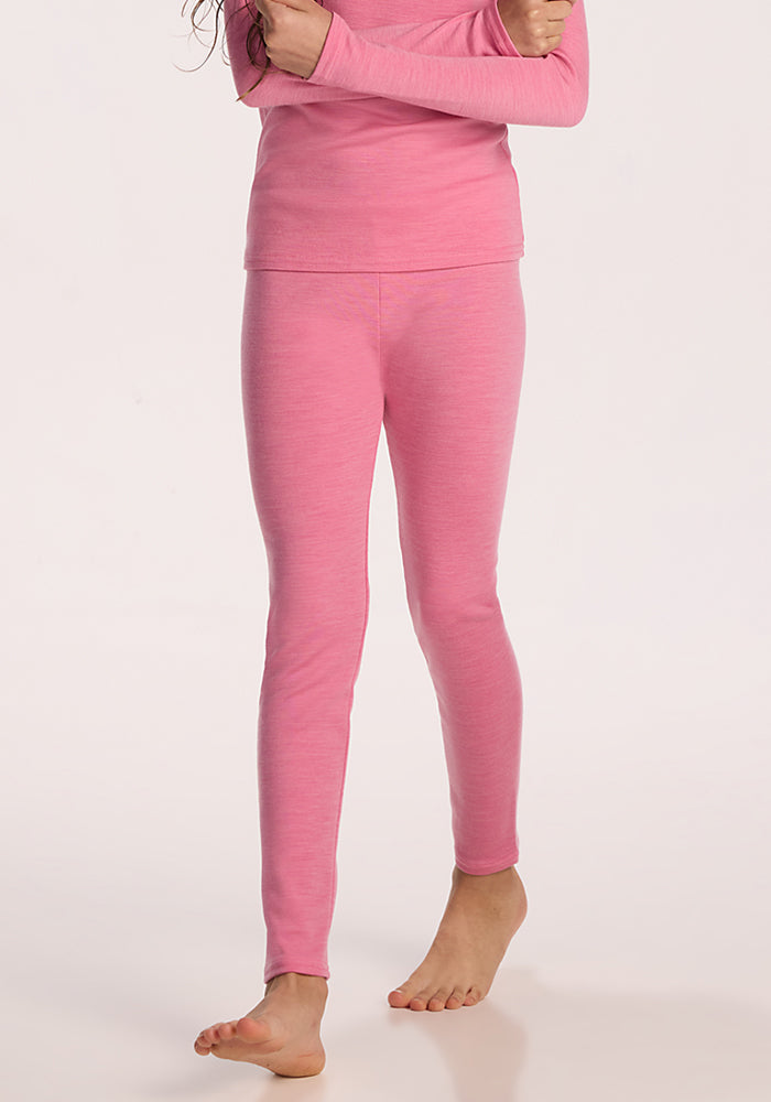 A child models the Woolx Kids Explorer Base Layer Bottoms in Pinky Promise, standing barefoot against a light background with their face not shown.