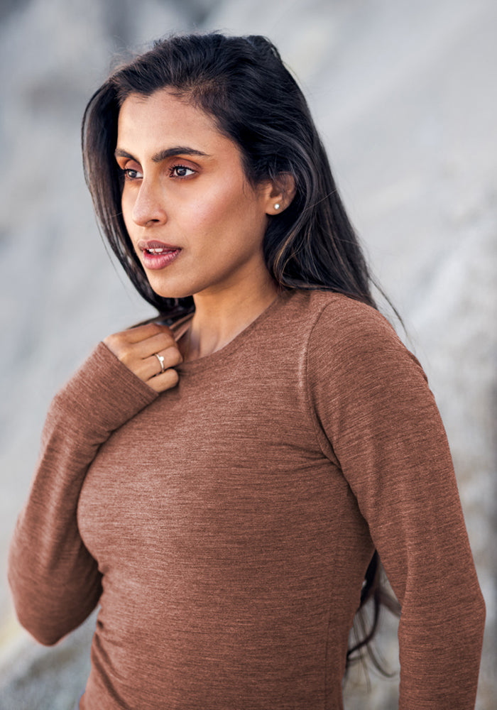Woman with long dark hair wears the Woolx Hannah Long Sleeve Top in Sable Heather, standing outdoors and looking sideways.