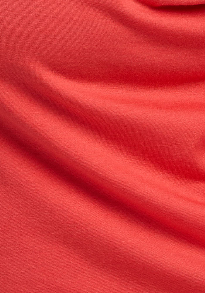 Close-up of Woolx Junie V Neck - Hibiscus shows soft folds and shadows, highlighting its textured Merino wool fabric.