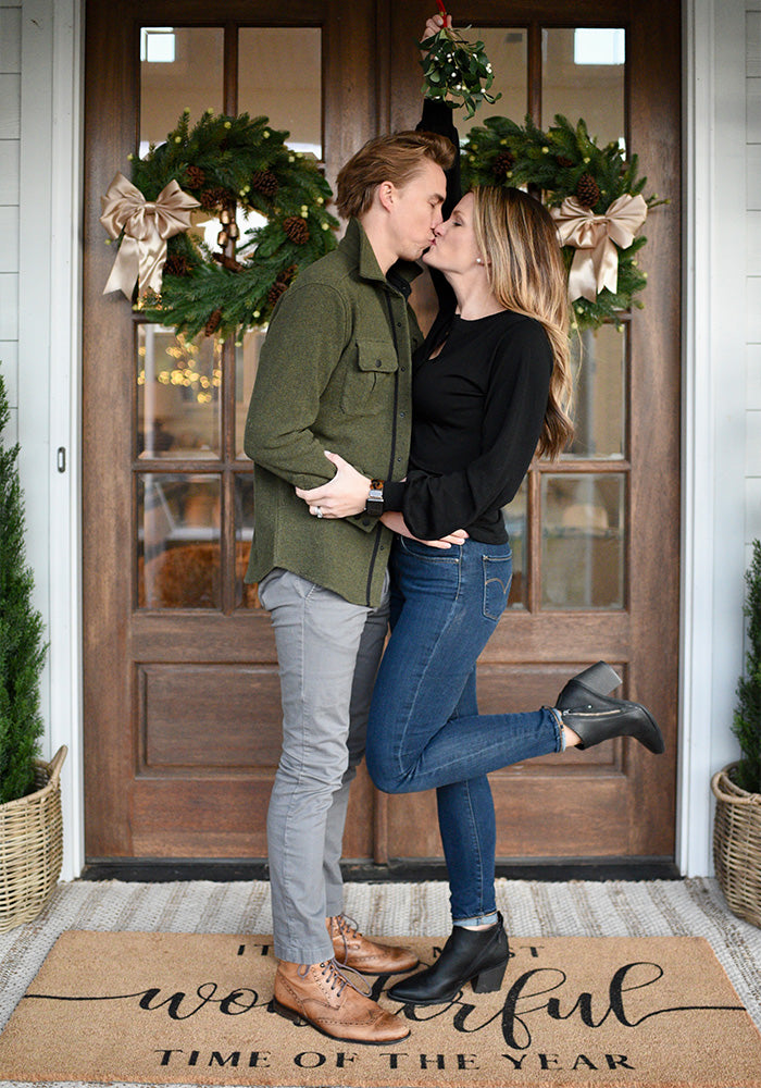 Couple wearing Woolx kissing on Holiday decorated front porch
