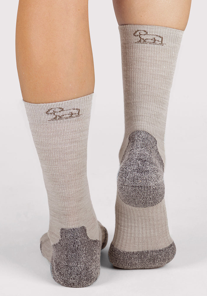 A person wearing Woolx Womens Harbor Crew Sock - Icicle: light gray Merino wool socks with darker gray heels/soles, lightweight cushioning, moisture-wicking, and a small embroidered sheep near the top back.