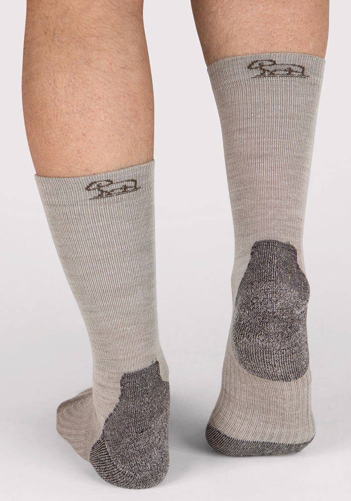 A close-up of the back of a person's lower legs wearing Woolx Mens Harbor Crew Sock - Icicle, featuring moisture-wicking Merino wool and dark gray heel and toe patches, shown on a plain white background.