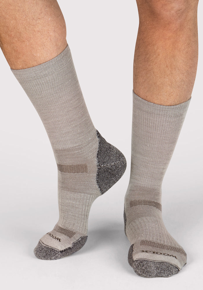 A person wears Woolx Mens Harbor Crew Socks in Icicle, temperature-regulating Merino wool with moisture-wicking soles and contrasting gray heels and toes. One foot is flat, the other raised to reveal the sock’s sole against a light background.