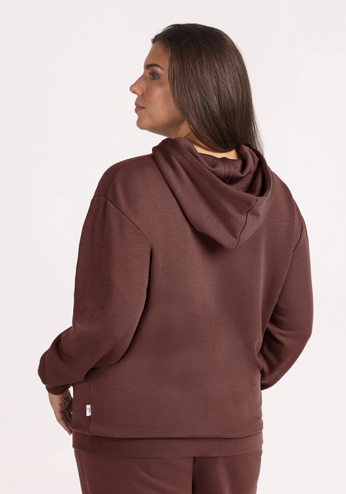 Woman with long brown hair wearing the Woolx Avery Hoodie in Canyon Clay, back to camera, light background.