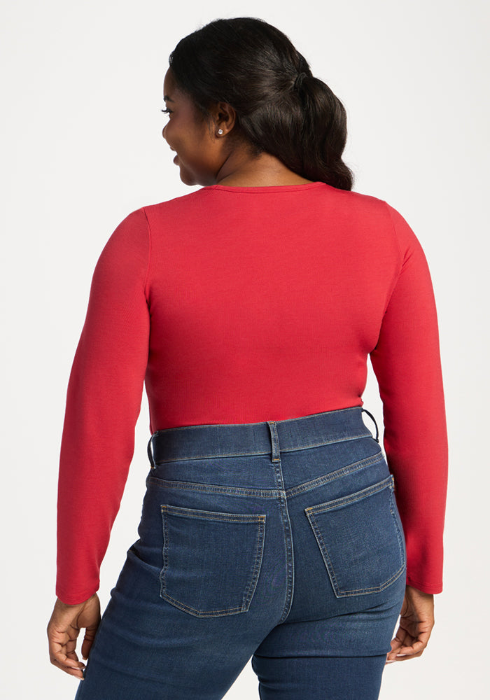 Woman in Woolx Margot Bodysuit - Maraschino Cherry and blue jeans, facing away against a white background.