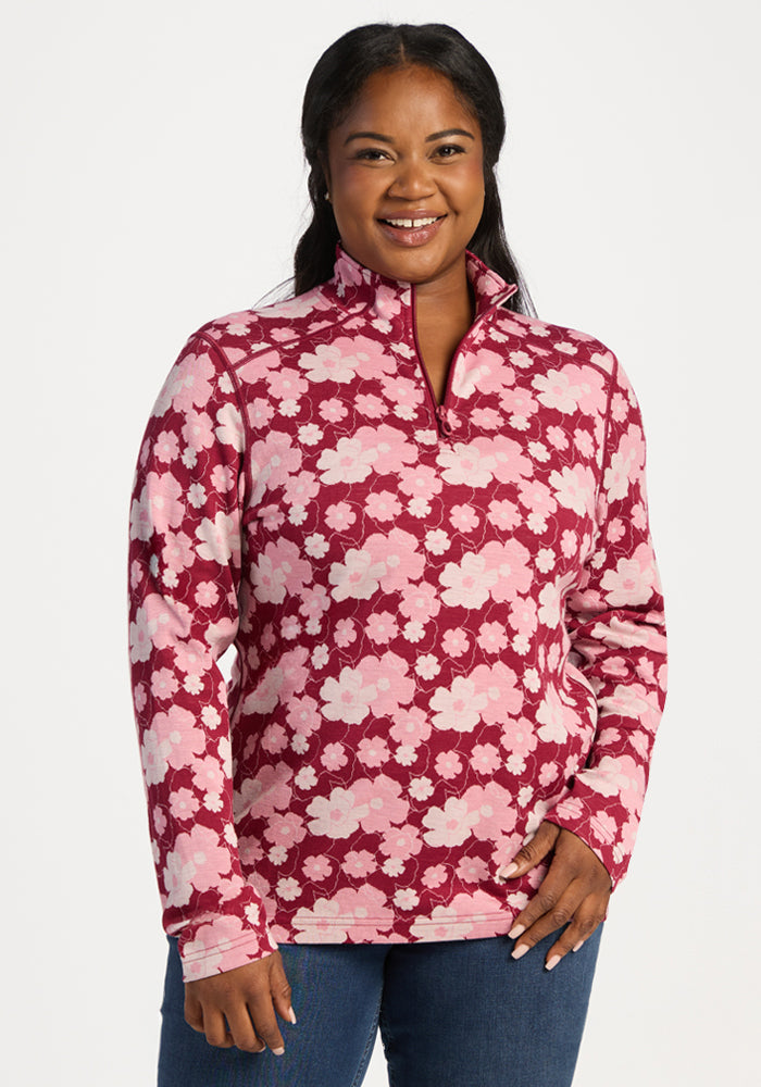 Smiling woman in the Woolx Emi 1/4 Zip - Floral Crush pullover with jeans, standing against a white background. 
