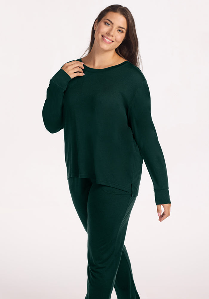 A woman wearing a wrinkle-resistant, dark green Ashlie Lounge Top - Deep Pine and matching pants.