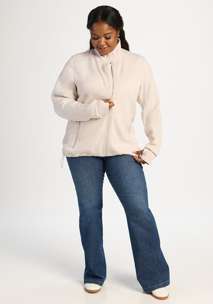 A woman wearing an ecru Woolx Teddy Sweatshirt in ultra-heavyweight merino wool with a zip-up and blue jeans.