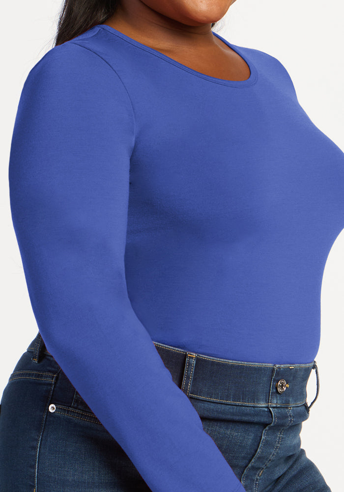 Woman wears Woolx Margot Bodysuit in royal blue with high-waisted dark jeans, shown from shoulders to hips.