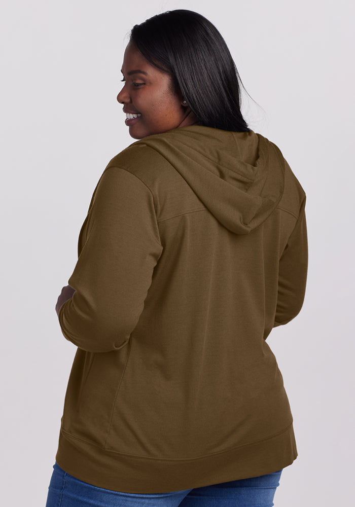 Woman in a Woolx Ryann Hoodie - Olive Leaf, smiling with long dark hair and blue jeans against a plain backdrop.