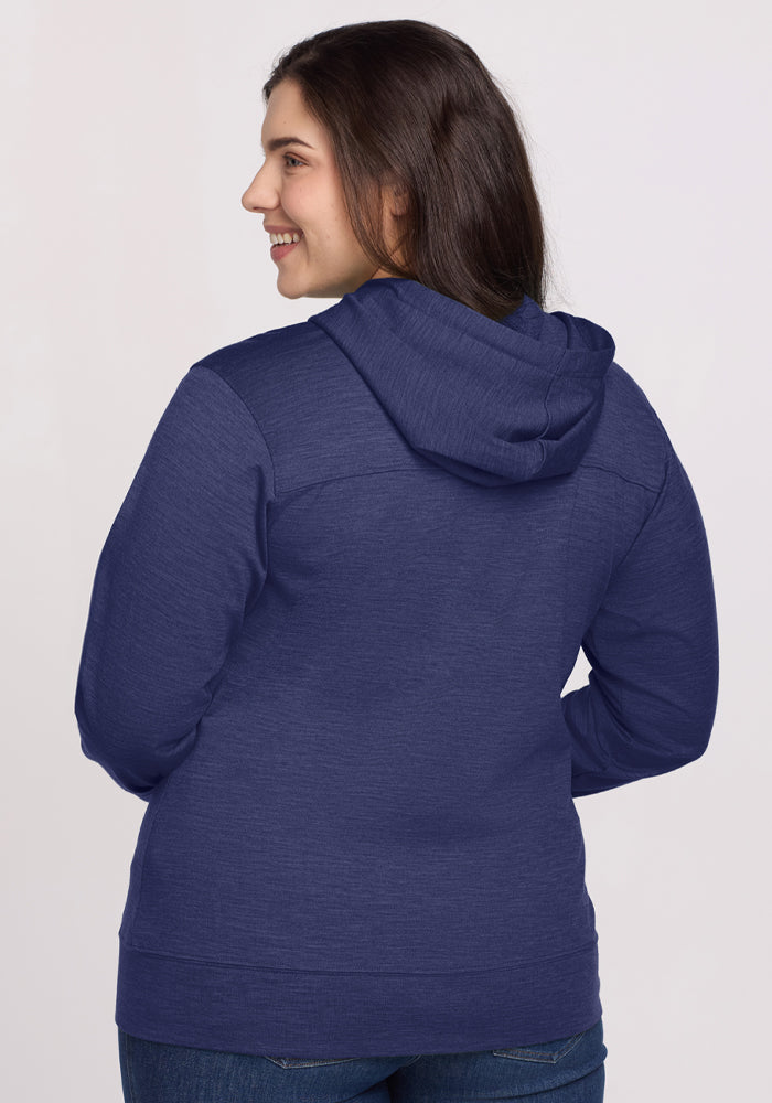 Woman wears Woolx Ryann Hoodie - Twilight Storm, facing away, smiling with hands on hips against light background.
