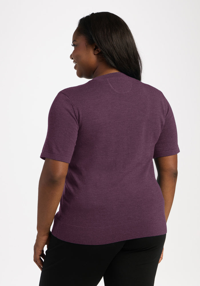 Woman facing away in Woolx Anna Crew Sweater - Purple Iris, short sleeves, black pants, against white background.
