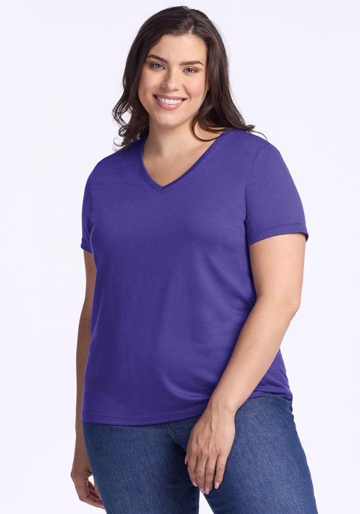 Woman smiling in the Woolx Junie V Neck - Berry Indigo, relaxed fit, paired with blue jeans against a light background. 