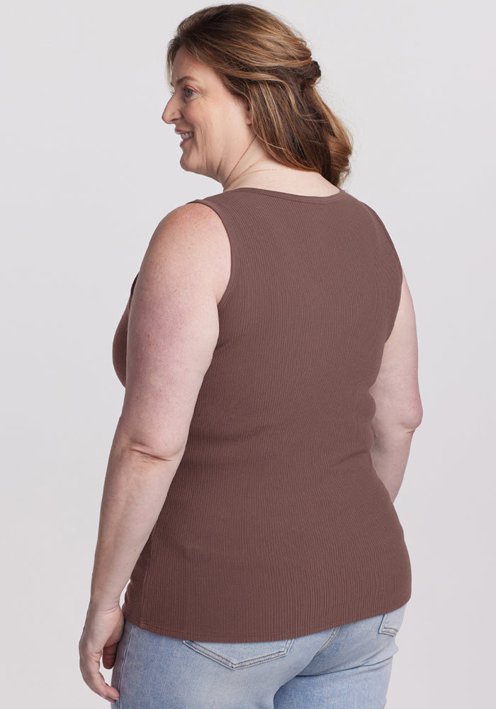 A woman with light skin and brown hair smiles, wearing the Woolx Vivi Ribbed Tank in Peppercorn and light blue jeans.