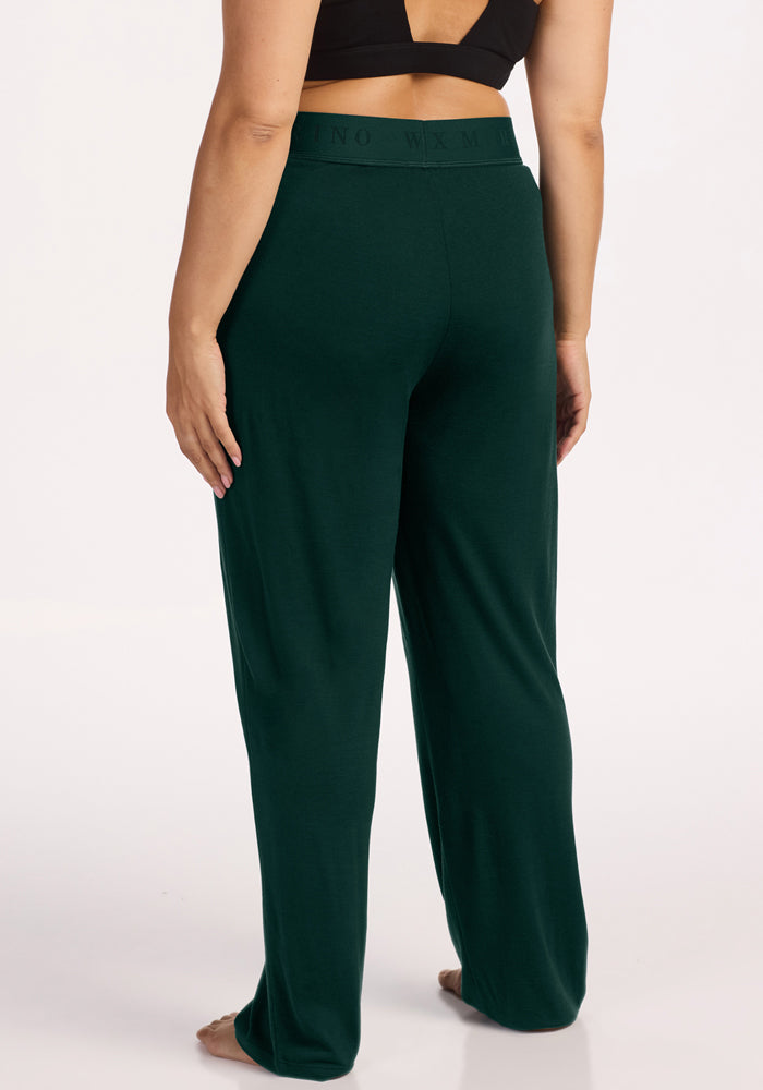 A person seen from behind wearing dark green Woolx Maya Lounge Pants - Deep Pine with an elastic waistband.