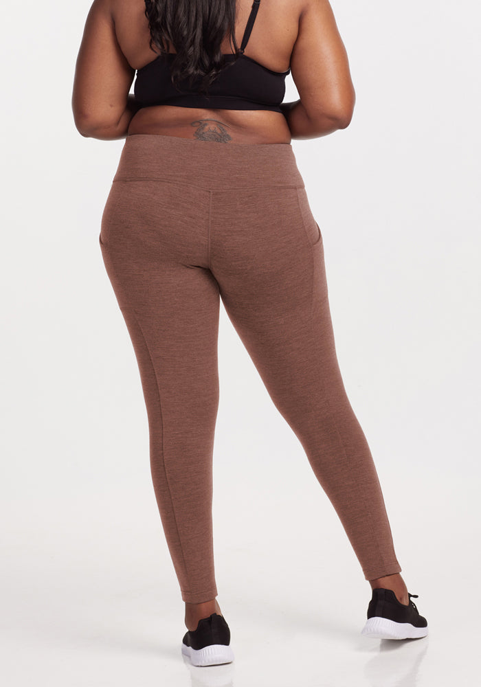 Woman in Woolx Piper Pocket Leggings - Sable Heather and black sports bra, back to camera on white backdrop.