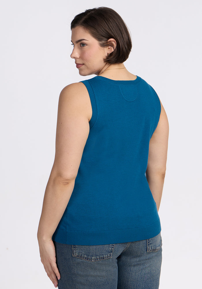 A woman with short brown hair models the Woolx Chessy Tank Top in Moroccan Blue, showing the sleeveless back view, paired with blue jeans against a plain white background.