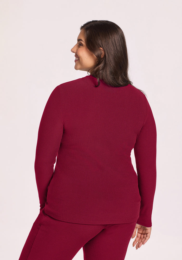 Woman wears Woolx Hadley Ribbed Crew in Beet Red, smiling with her back turned to the camera.