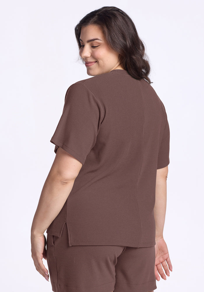 Woman in the Woolx Delia Ribbed Short Sleeve—Peppercorn, smiling and facing away with wavy brown hair.
