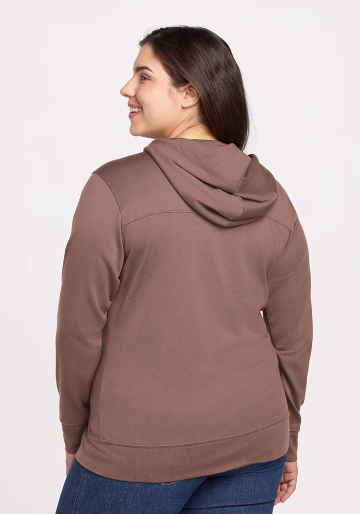 Smiling woman in Woolx Ryann Hoodie - Toasted Almond, shown from the back—a cozy travel must-have.