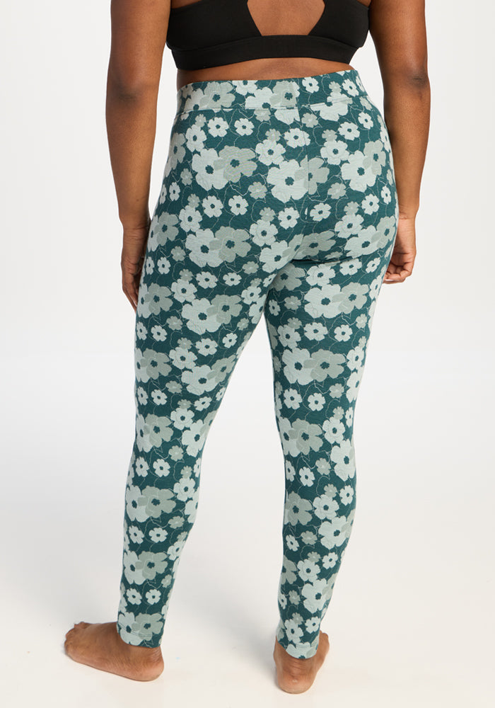 Person standing barefoot in Woolx Taylor Baselayer Leggings - Coastal Wildflower, black top, back view, white background.