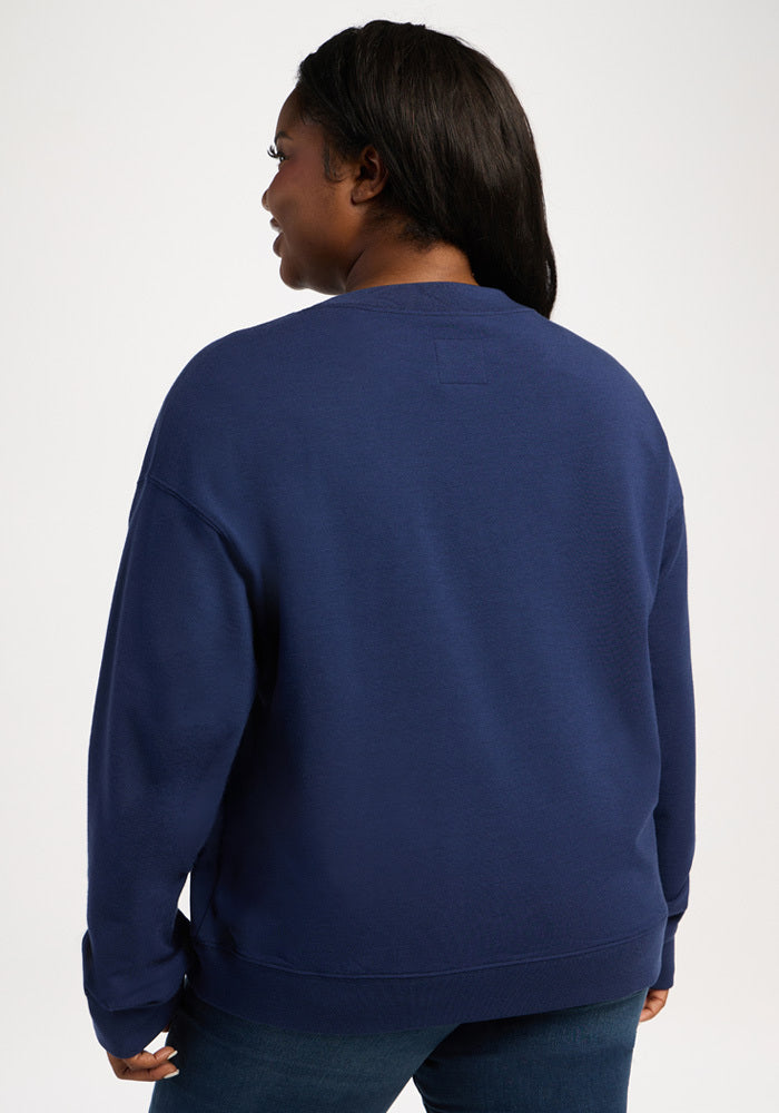A person viewed from the back wearing a dark blue moisture-wicking Molly Crewneck - Ocean Cavern merino wool sweater.
