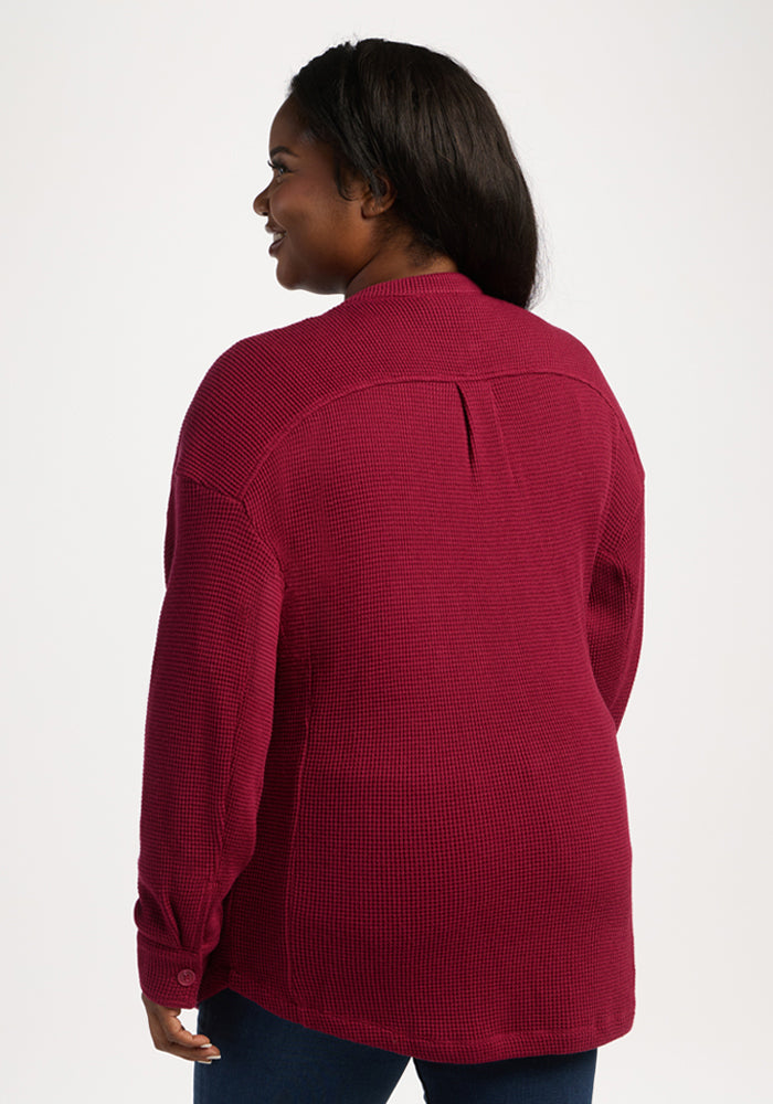 Woman in a Woolx Oaklynn Waffle Shacket in Beet Red and jeans, smiling with her back to a white background.