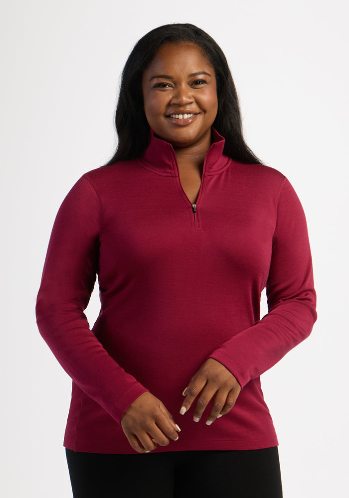 Woman smiles in a Woolx Brooke 1/4 Zip - Beet Red, perfect for skiing, shown against a white background. 