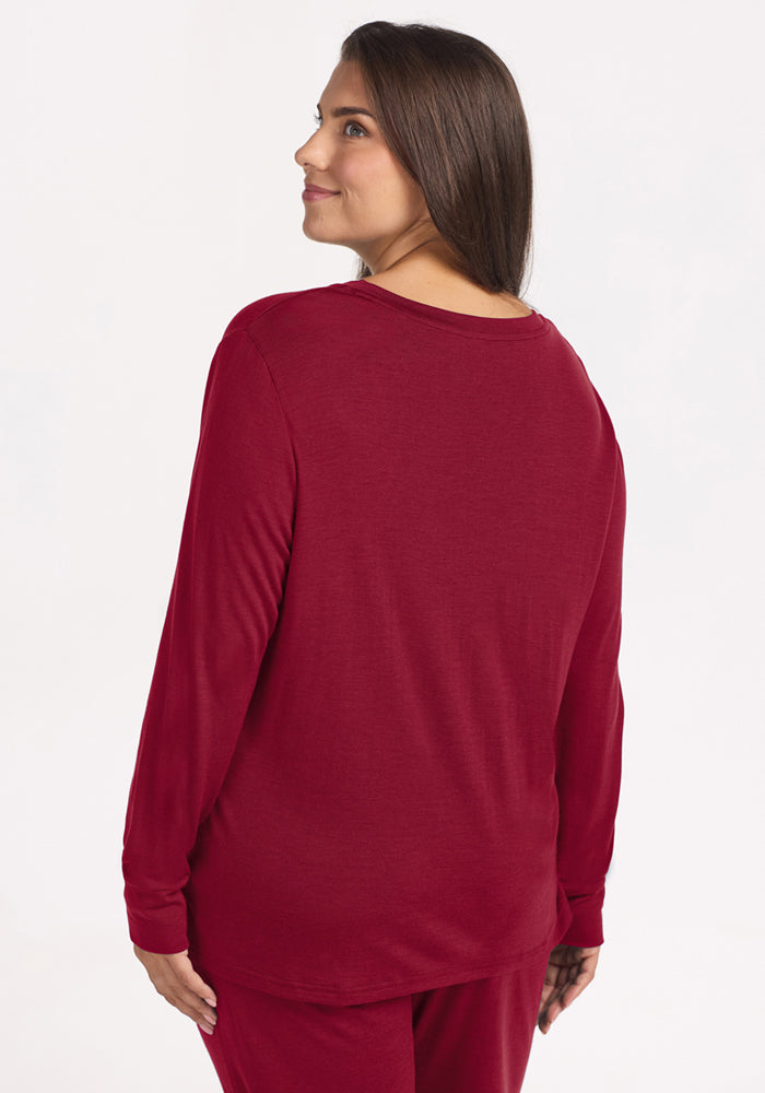 A woman seen from the back wearing an Ashlie Lounge Top - Beet Red long-sleeved merino wool travel top.