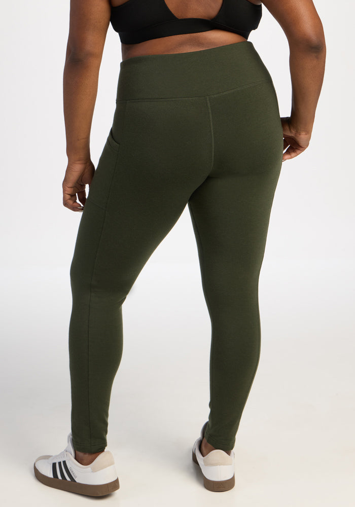 Person wears Woolx Frost Leggings - Duffel Bag, black sports bra, and white sneakers, standing with back to camera.